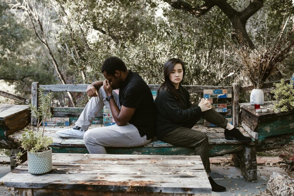 an upset couple sitting on a wooden bench